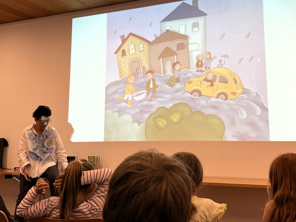 Vortragende von vorne, Kinder von hinten eine an die Wand gebeamte Zeichnung anschauend