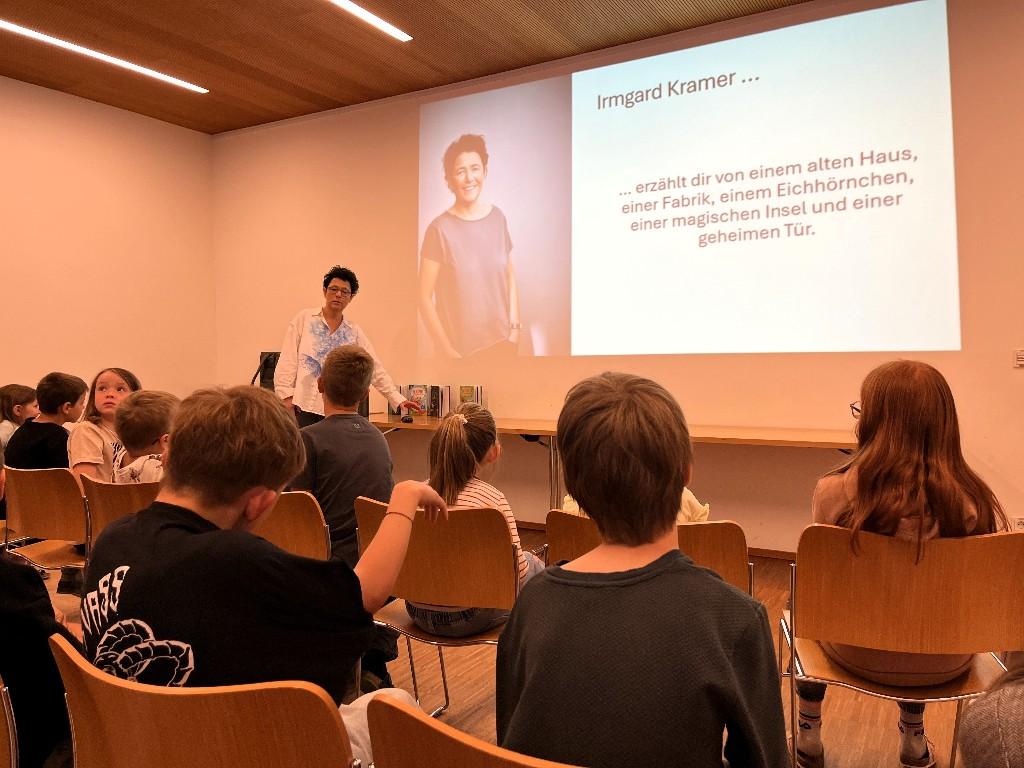 Vortragende steht vor den Kindern und zeigt eine Präsentation