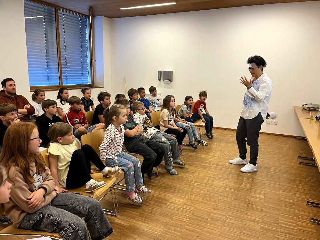 Vortragende steht vor den Kindern - von der Seite fotografiert
