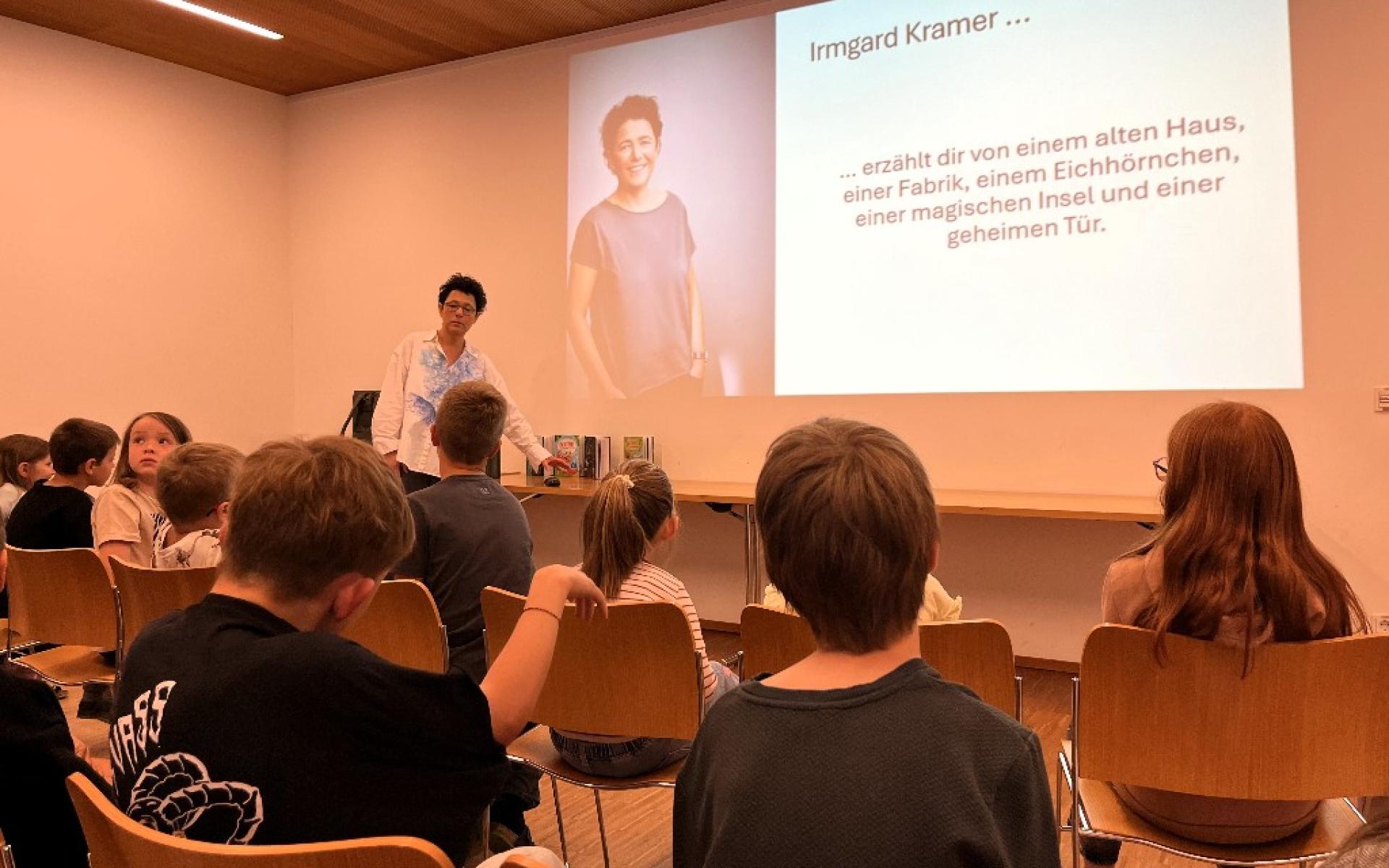Vortragende steht vor den Kindern und zeigt eine Präsentation