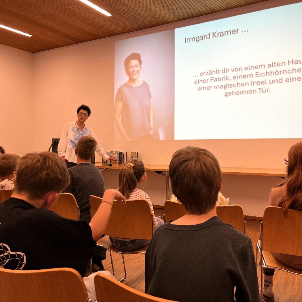 Vortragende steht vor den Kindern und zeigt eine Präsentation